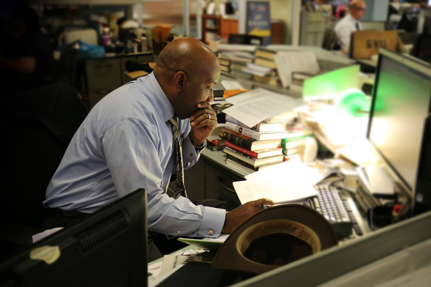 Errol Louis at desk looking at papers preparing for the upcoming New York U.S. Senate debate