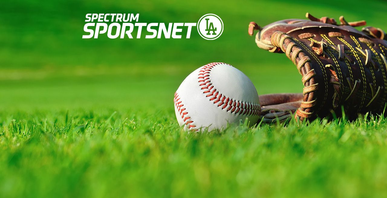 Baseball glove and ball sitting in the grass with Spectrum SportsNet logo